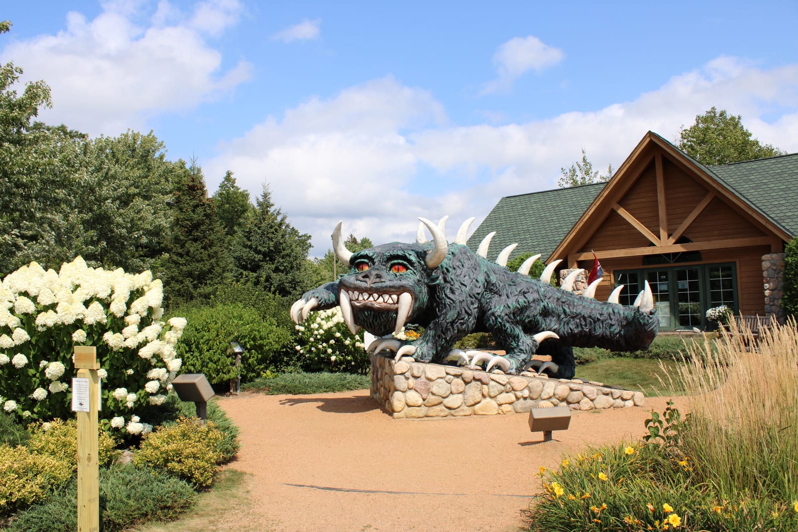 The Hodag statue surrounded by greenery outside the Rhinelander Area Chamber of Commerce in sunny conditions